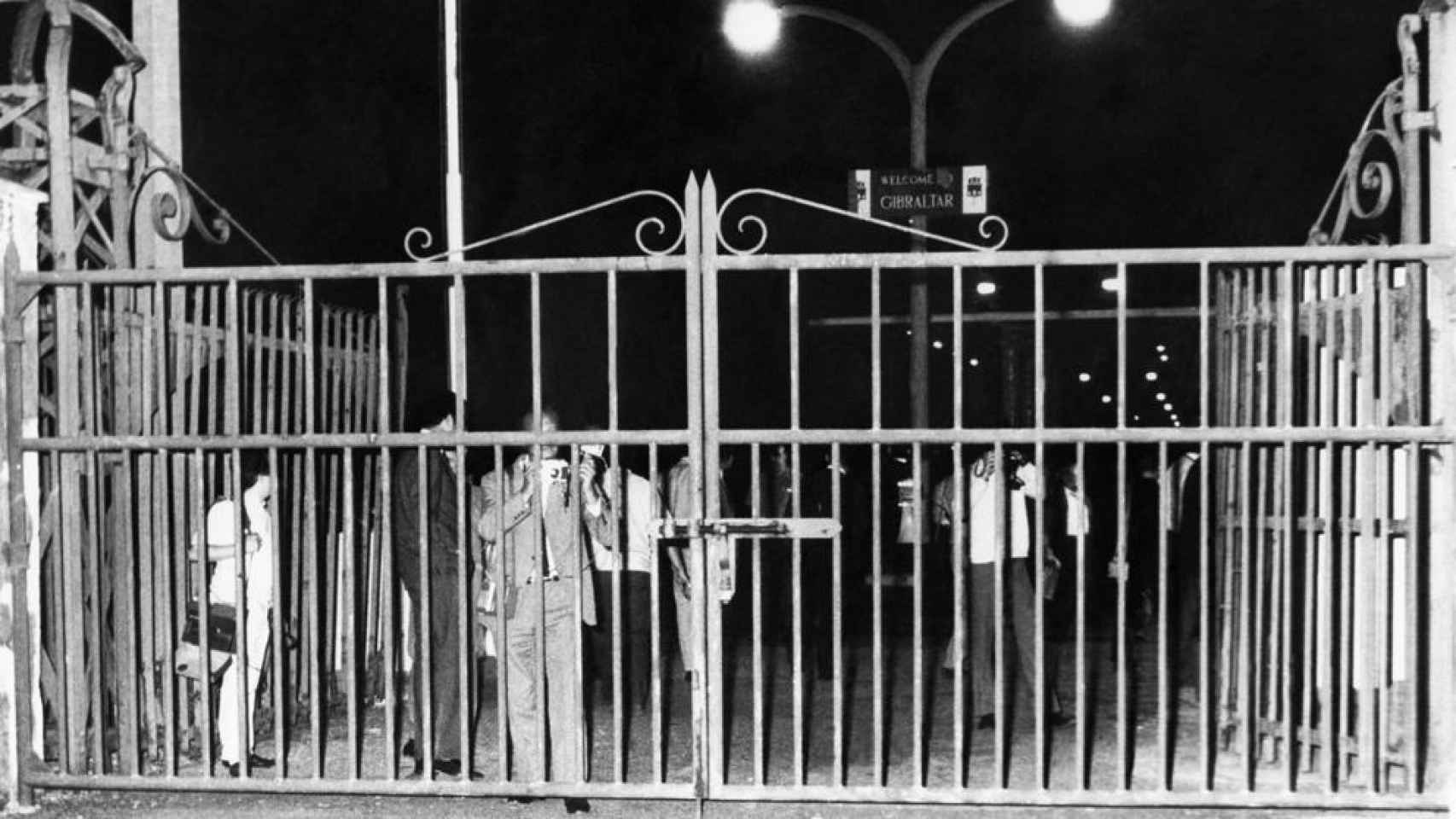 Foto tomada desde La Línea de la Concepción en la que periodistas británicos y gibraltareños observan cómo oficiales españoles cierran la verja (1969).