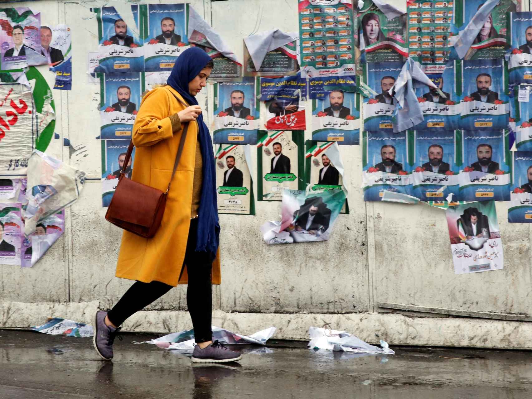 Una mujer iraní pasea delante de los carteles electorales