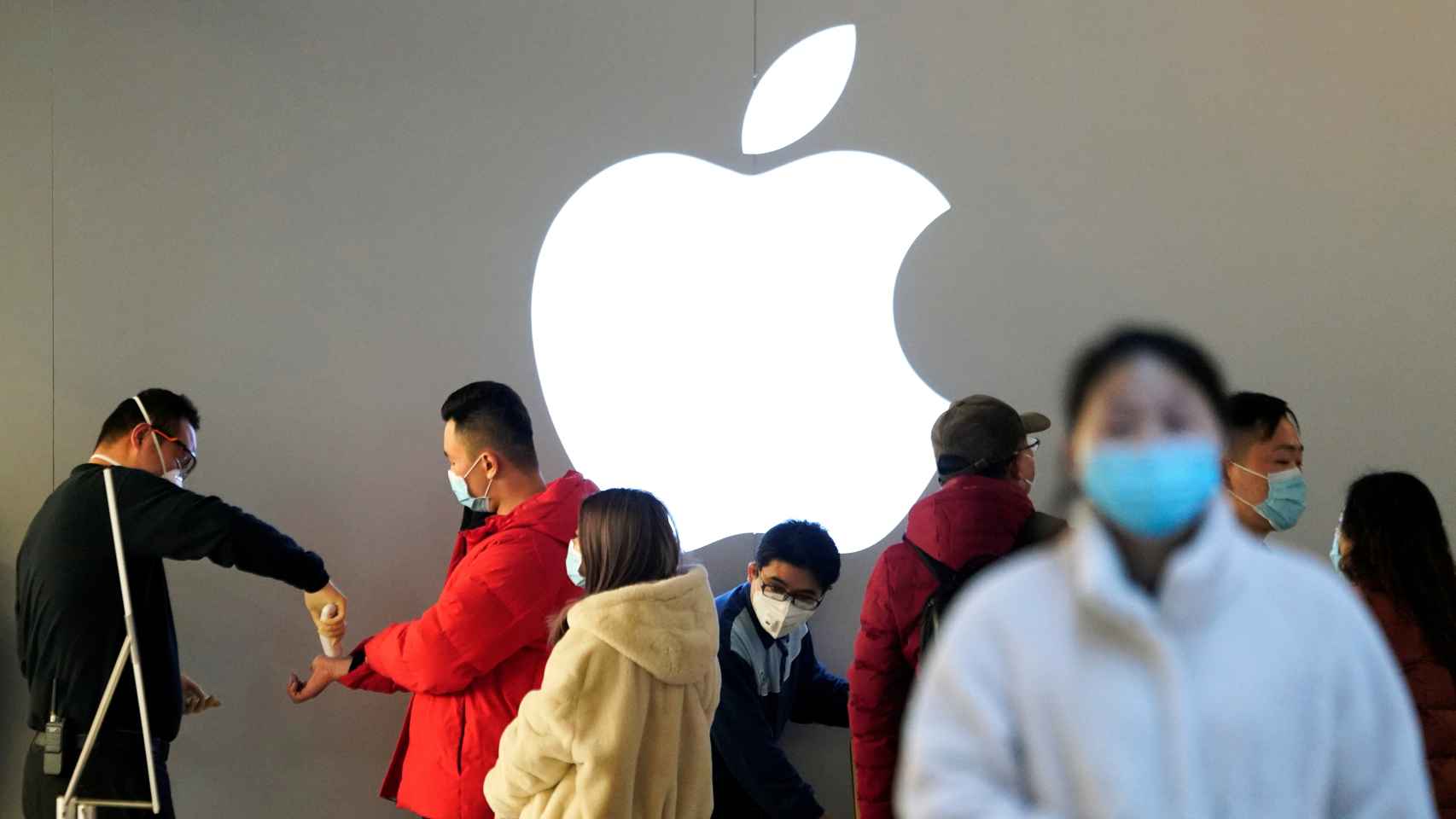 Personas con mascarilla son comprobadas antes de entrar en una Apple Store abierta en Shanghái