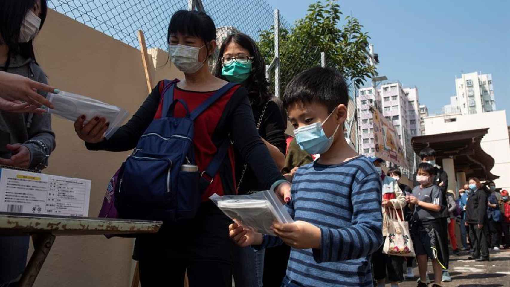 Ciudadanos de Hong Kong hacen cola para recibir mascarillas.