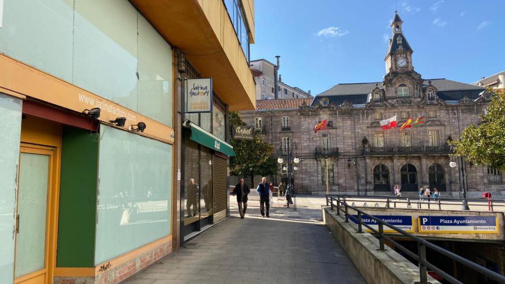 Dos locales comerciales cerrados y, de fondo, el Ayuntamiento de Torrelavega