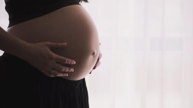 Una mujer embarazada se echa las manos a la barriga.