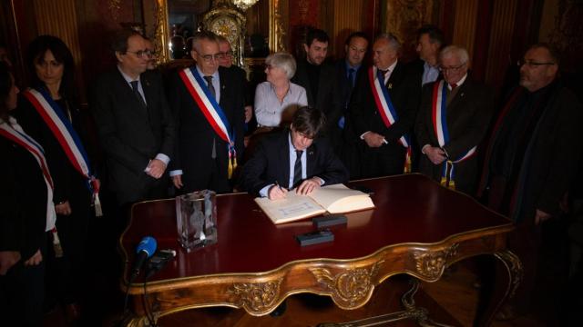 Carles Puigdemont, estampando la firma en el libro de Perpiñán.