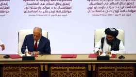 El líder talibán, Mullah Abdul Ghani Baradar, y el representante especial para la paz de EEUU, Zalmay Khalilzad, firmando el acuerdo.