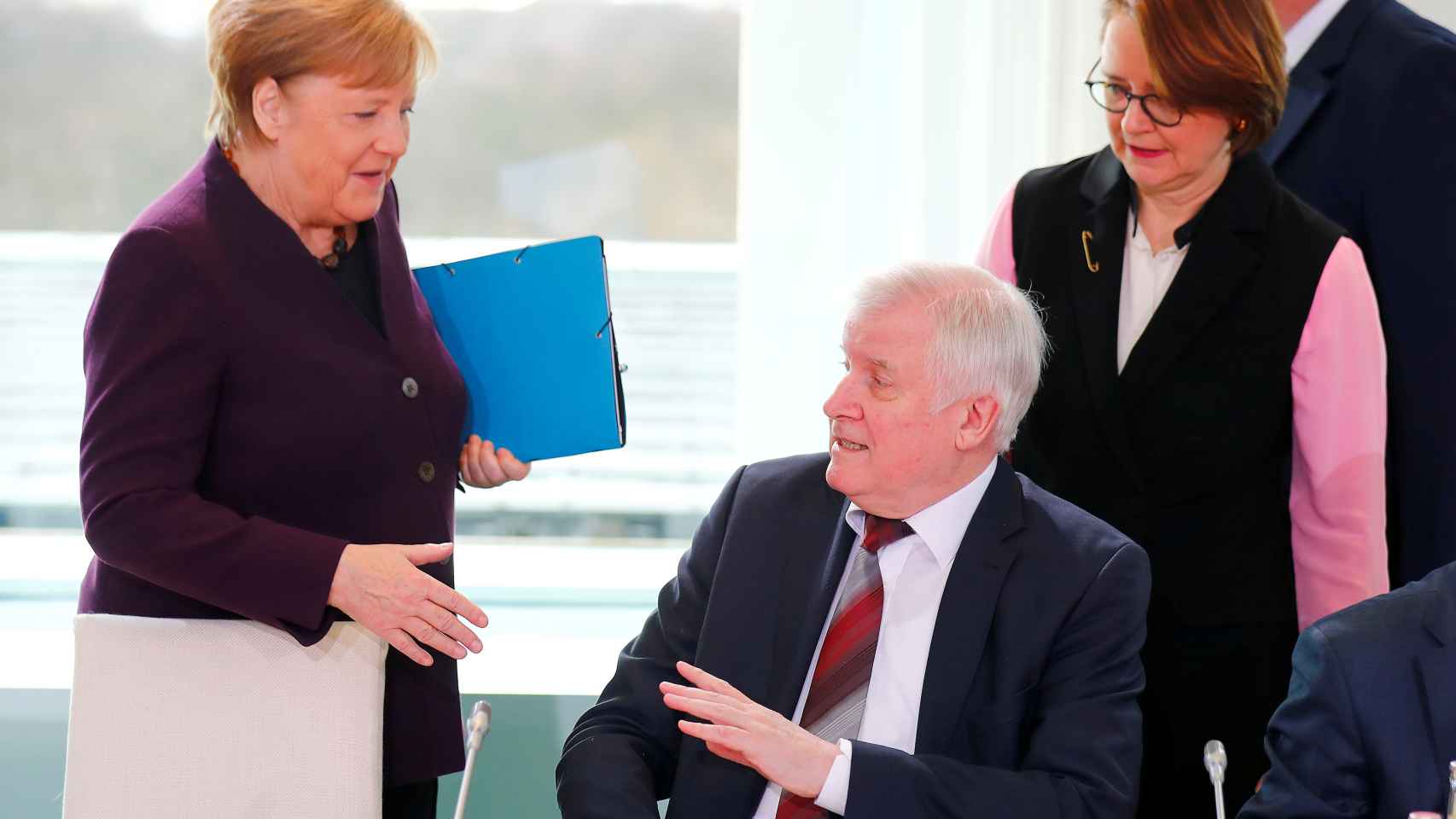 Angela Merkel intenta dar la mano al ministro de Interior, Horst Seehofer, que lo rechaza para evitar contagios.
