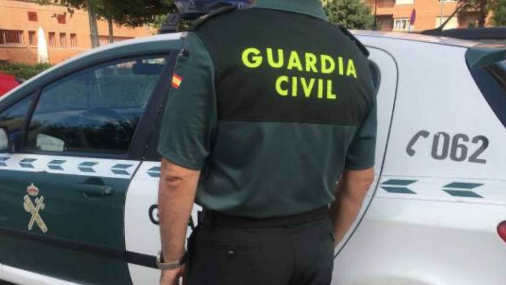 Un agente de la Guardia Civil junto a su coche.