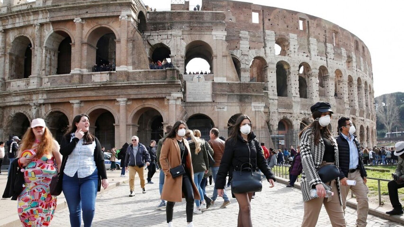Personas con mascarilla ante el Coliseo de Roma.