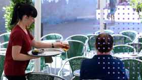 Una camarera atiende a un cliente en una terraza.