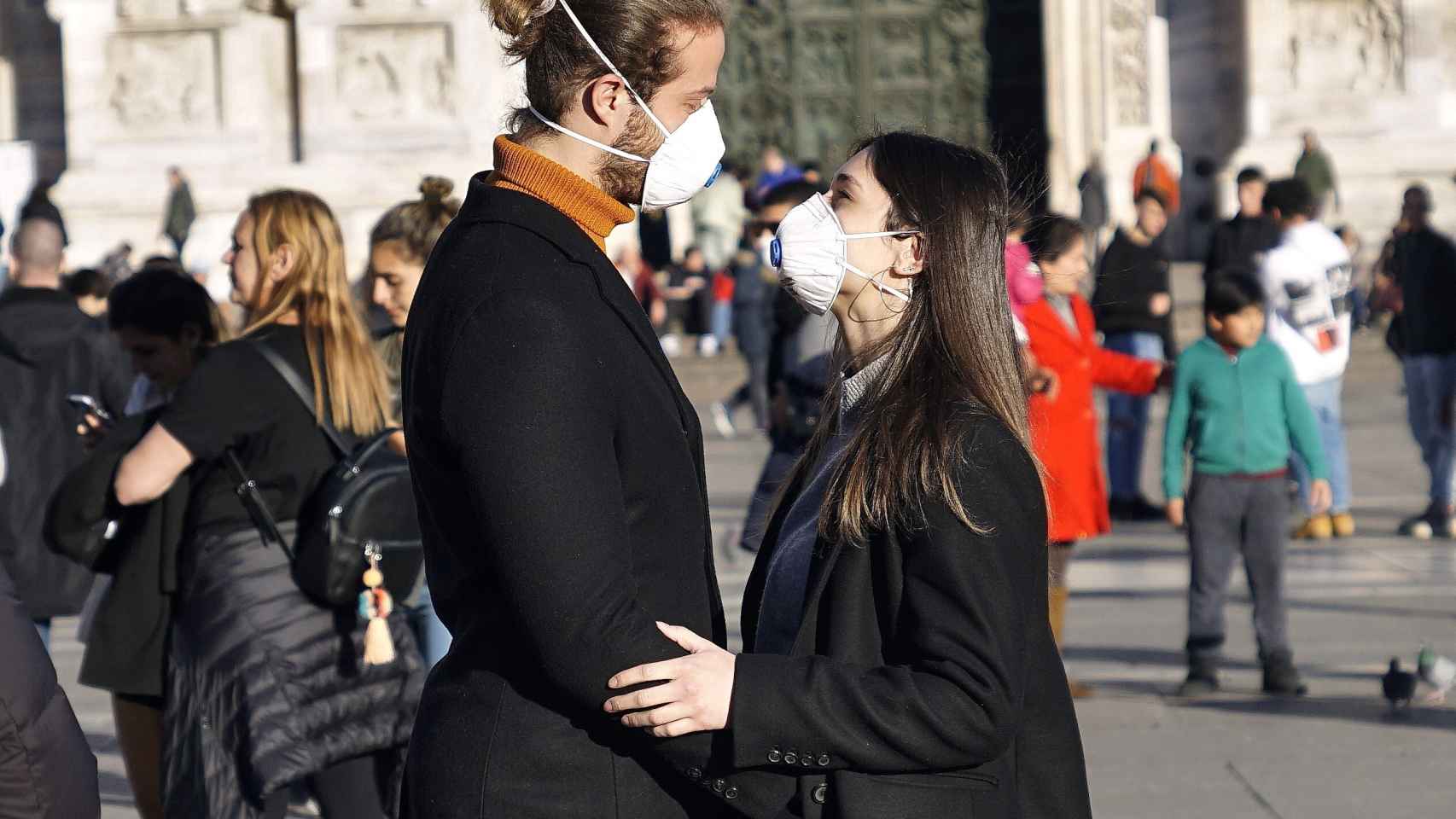 Una pareja con mascarillas se mira en Pisa