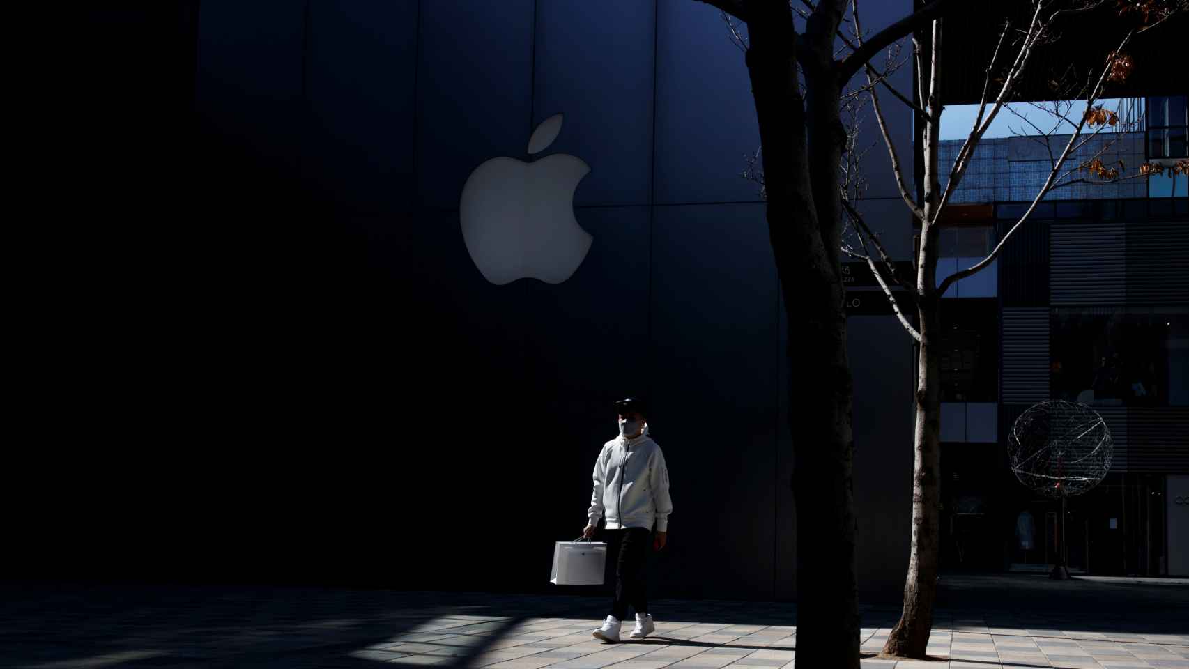 Una persona con mascarilla pasa al lado de una Apple Store en Beijing