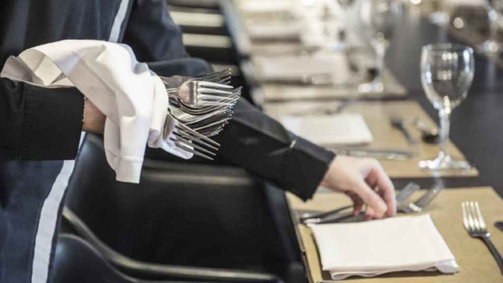 Un camarero pone la mesa en un restaurante.