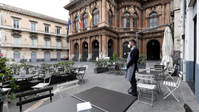 Un camarero espera clientes en la ciudad de Catania, Sicilia)