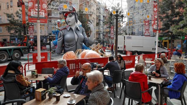 Varias personas disfrutan de un café ante una de las numerosas fallas del barrio de Ruzafa.