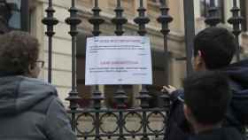 Dos escolares leen el cartel informativo sobre el cierre del colegio en Bilbao.
