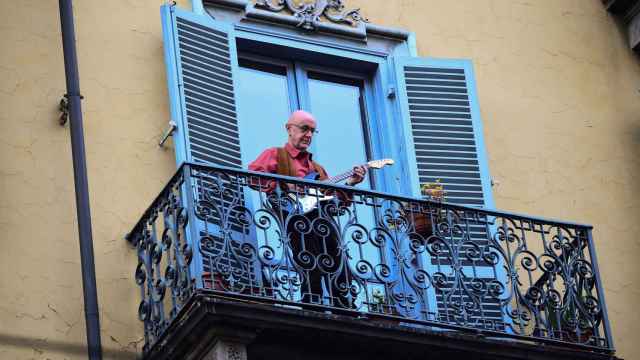 Un hombre toca la guitarra desde el balcón de su casa, en Turín.