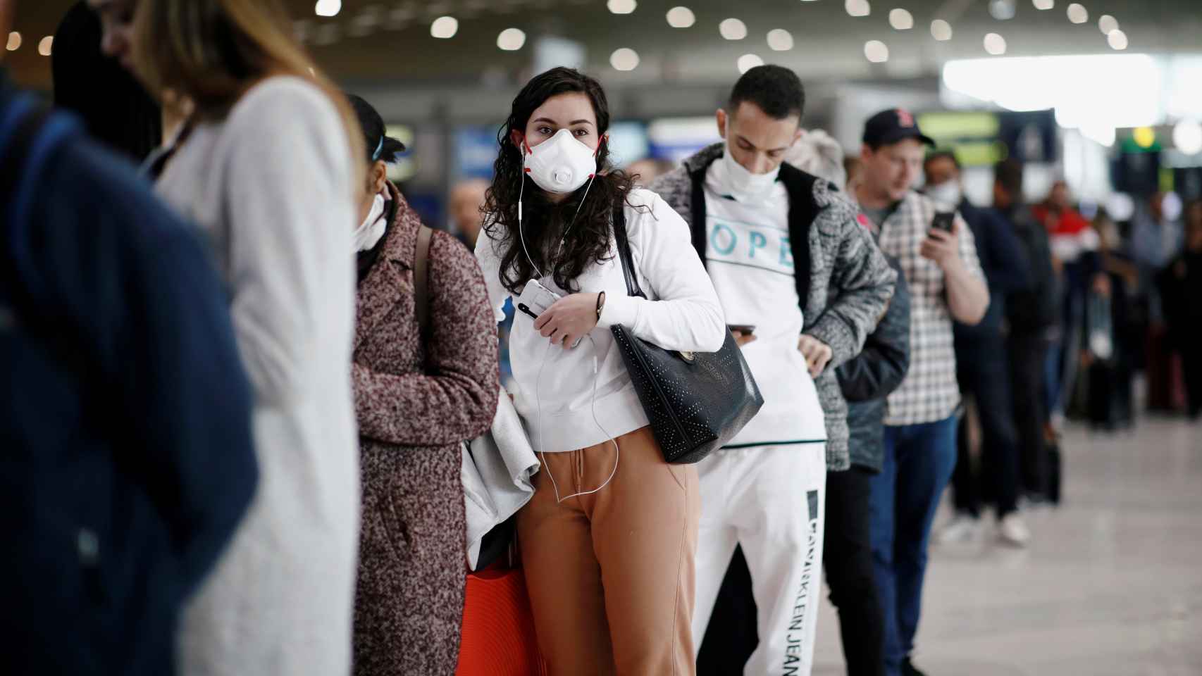 Cola de pasajeros con máscaras en el aeropuerto Charles de Gaulle en París