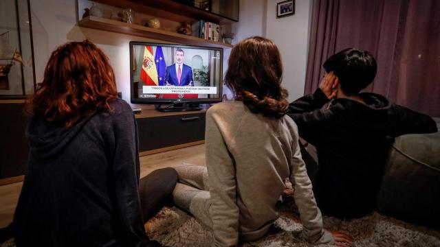 Tres personas ven el discurso extraordinario del rey Felipe VI.