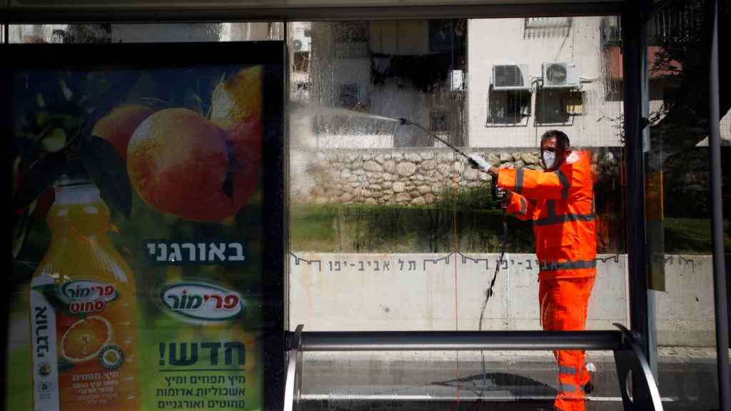 Un operario desinfecta una parada de autobús en Tel Aviv.