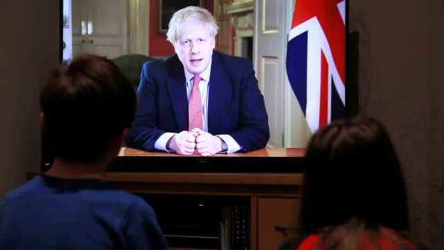 Ciudadanos británicos ven el discurso televisado de Boris Johnson, este lunes.
