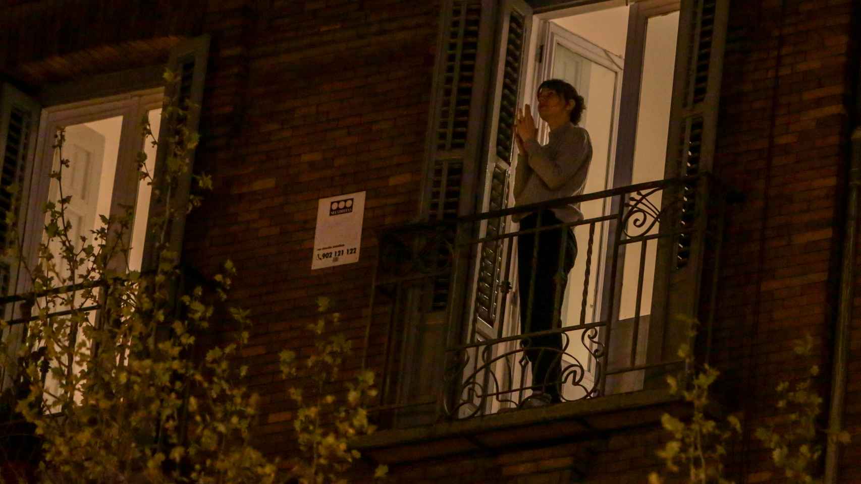 Una mujer aplaude desde su balcón por la labor que están realizando los sanitarios, en Madrid.