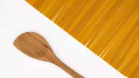 Una cuchara de madera junto a unos espaguetis.