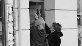 Imagen de archivo de dos mujeres abriendo la persiana de un negocio.