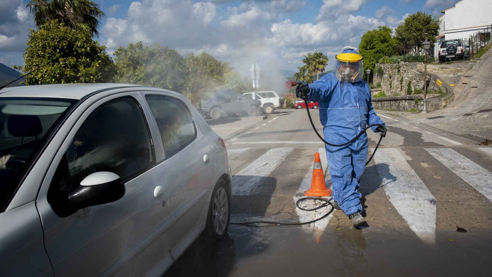 Un operario desinfecta con agua y lejía el coche que pasa por el punto de control sanitario de Zahara de la Sierra (Cádiz).