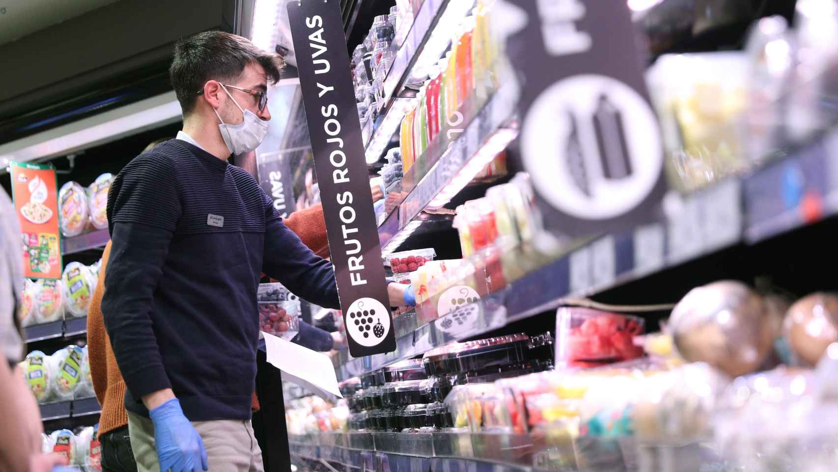 Varias personas hacen la compra con mascarilla y guantes en un supermercado en Madrid durante el confinamiento.