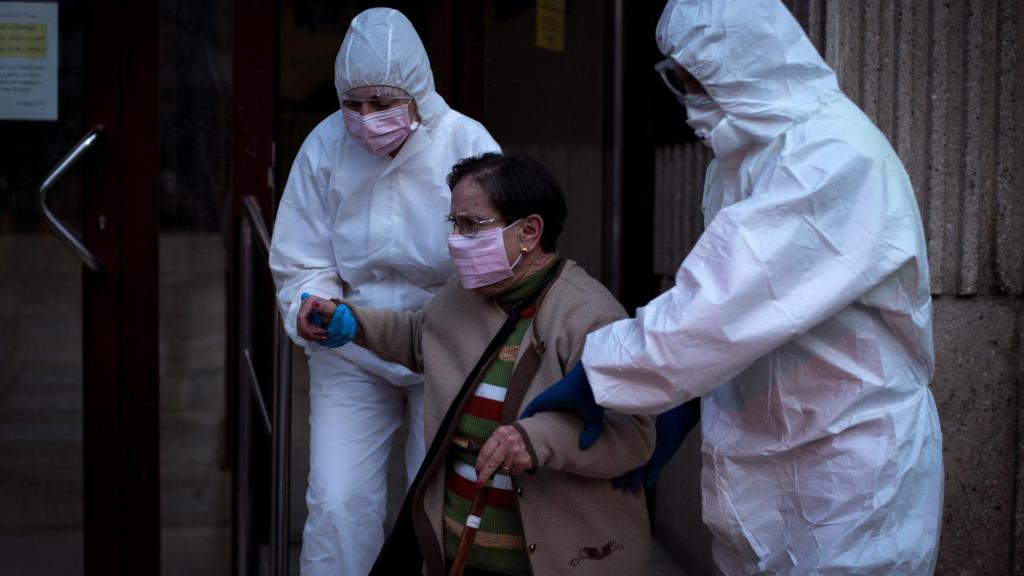 Dos sanitarios trasladan a una anciana a la ambulancia.