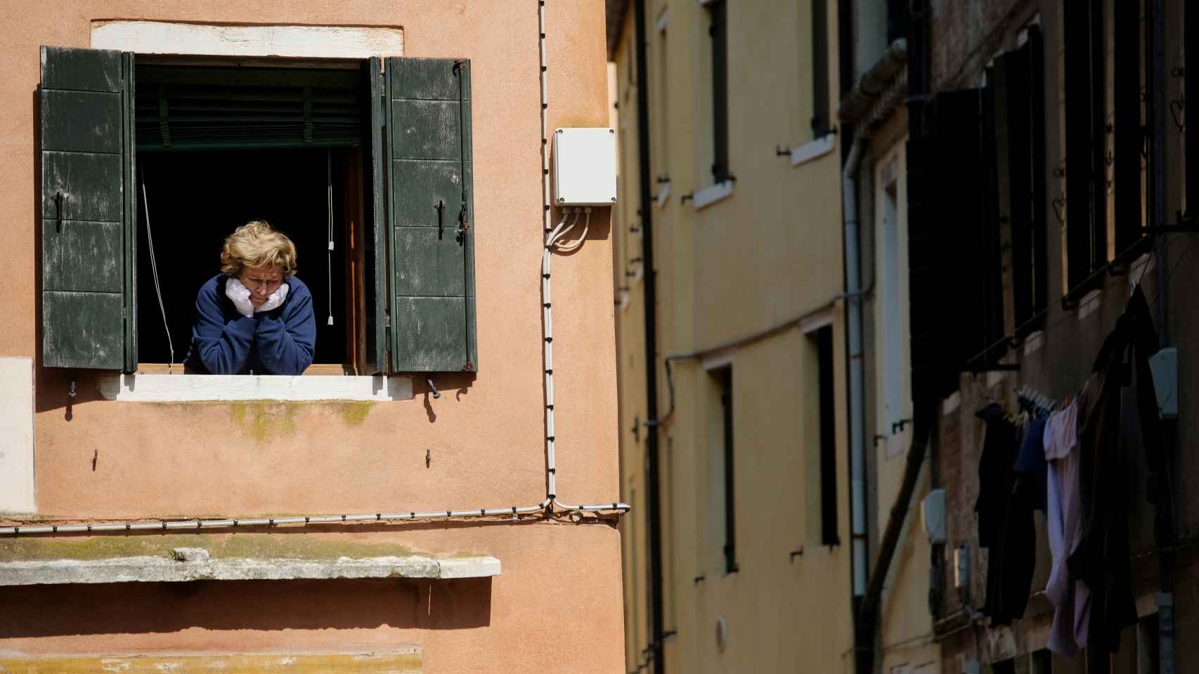 Una mujer se asoma a la ventana en su confinamiento en Venecia.