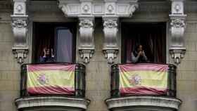 Dos ciudadanos aplauden desde los balcones de sus casas, en Madrid.