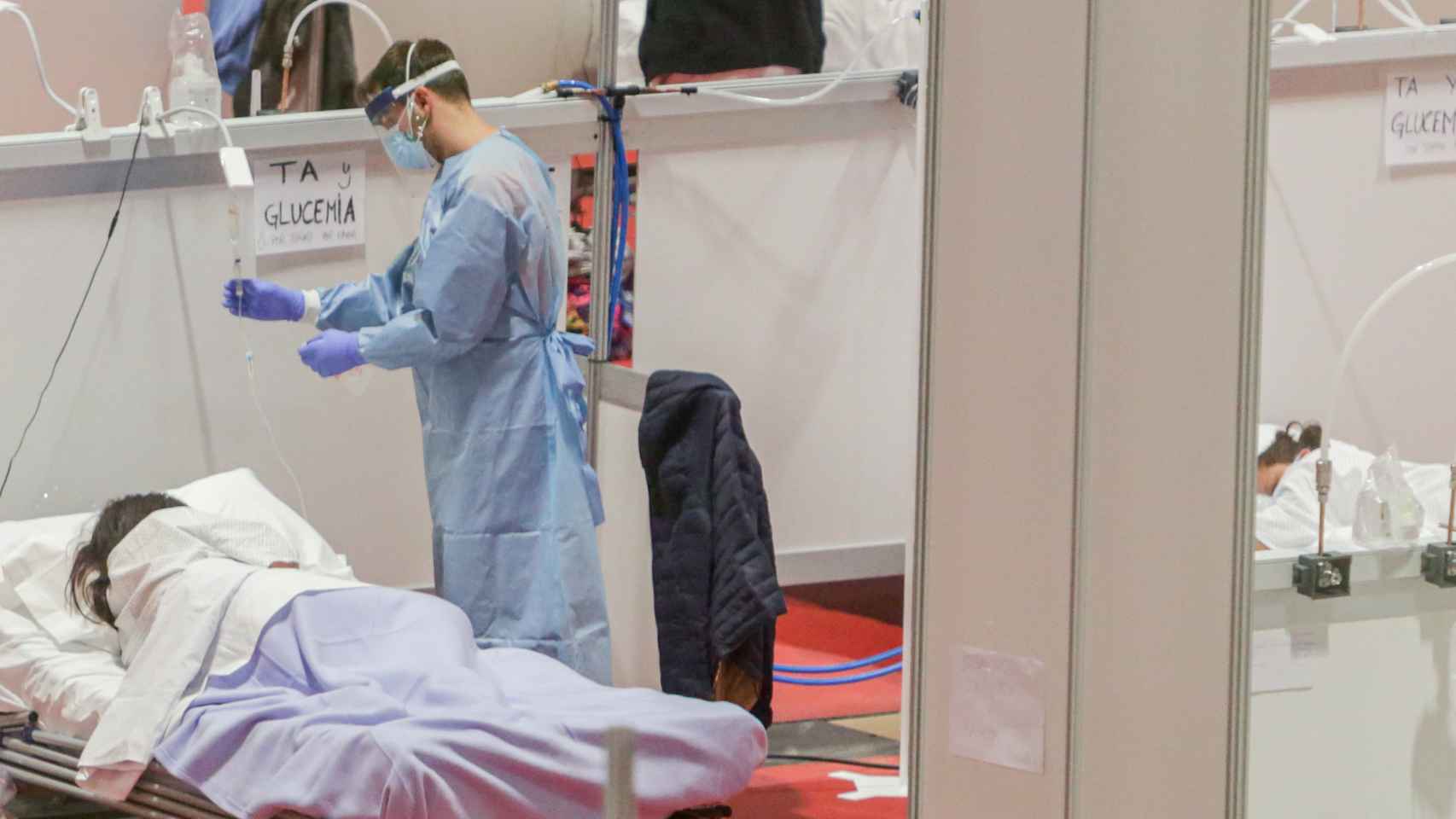 Un sanitario atiende a una paciente ingresada por coronavirus en el Hospital de Campaña montado en el recinto madrileño de IFEMA.