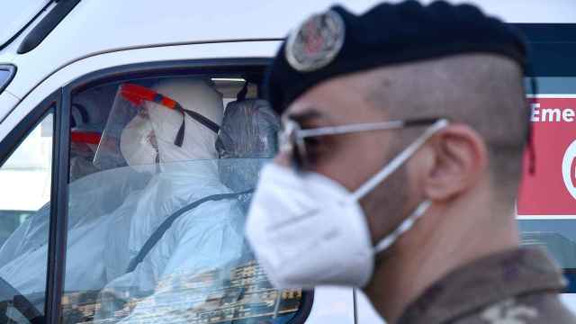 Un soldado frente a trabajadores sanitarios con mascarilla en Génova