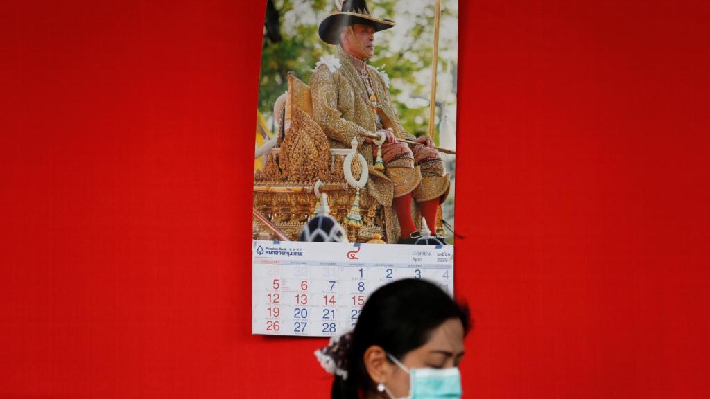 Una ciudana de Tailandia, en una calle de Bangkok, con el retrato del rey al fondo.