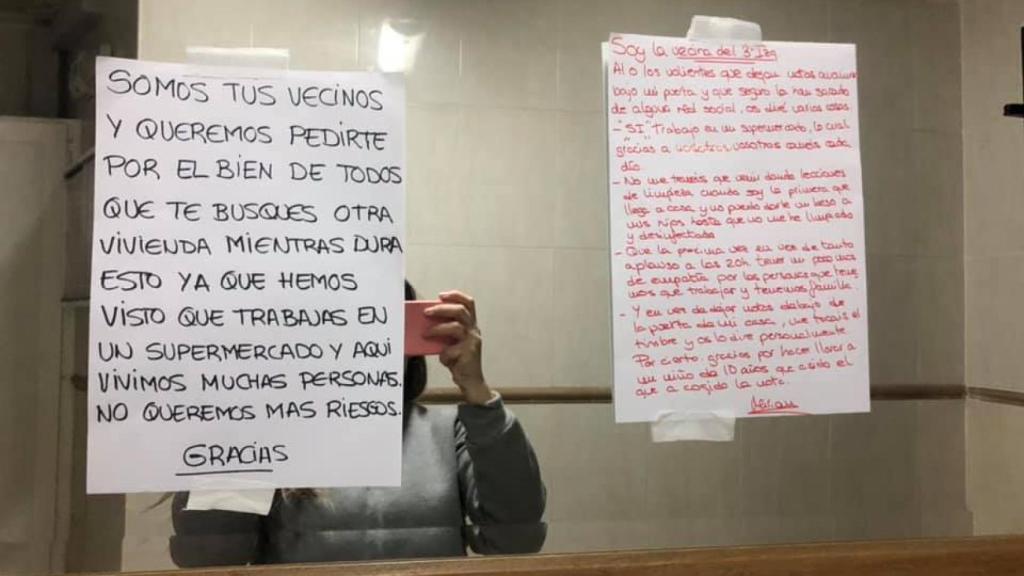 Una vecina, en el bloque de pisos de Cartagena, sacando una foto de la nota anónima que han enviado a Miriam para que se vaya del edificio.