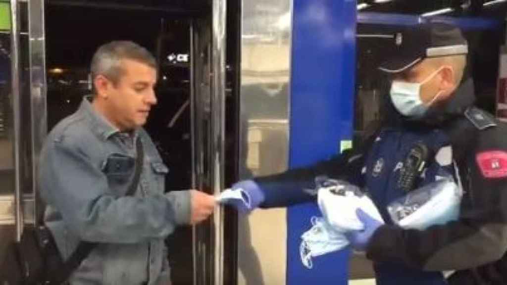 Un policía municipal reparte mascarillas este lunes en el Metro de Madrid.
