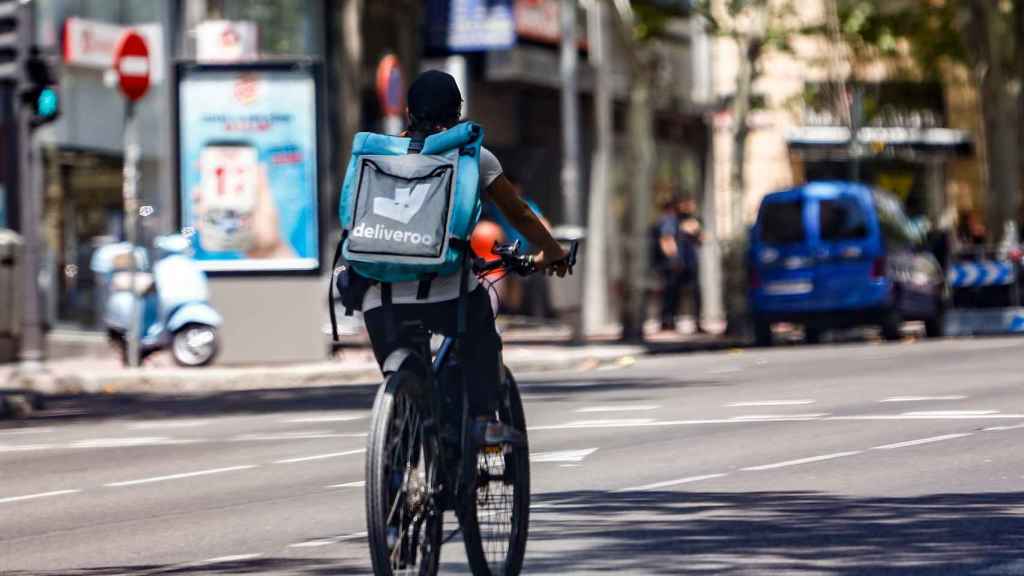 Un 'rider' de la compañía de comida a domicilio, Deliveroo, circula con su bicicleta por una calle de Madrid en agosto de 2020.