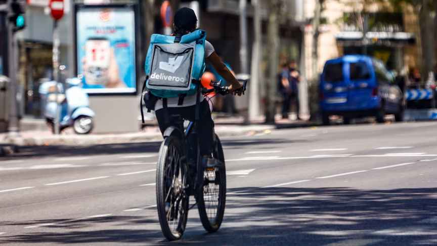 Un 'rider' de la compañía de comida a domicilio, Deliveroo, circula con su bicicleta por una calle de Madrid en agosto de 2020.
