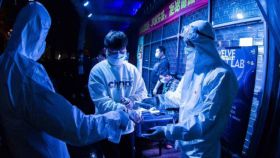Unos empleados toman la temperatura a un joven en la entrada a una discoteca china.