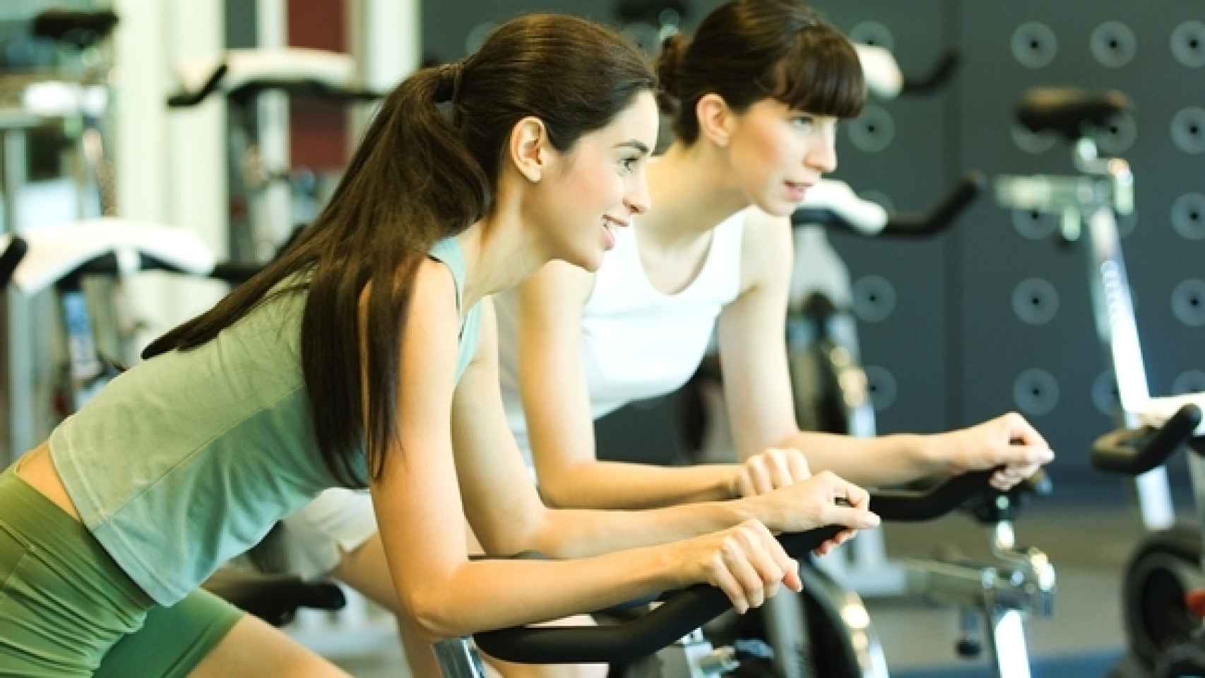 Dos mujeres hacen ejercicio en bicicletas estáticas.