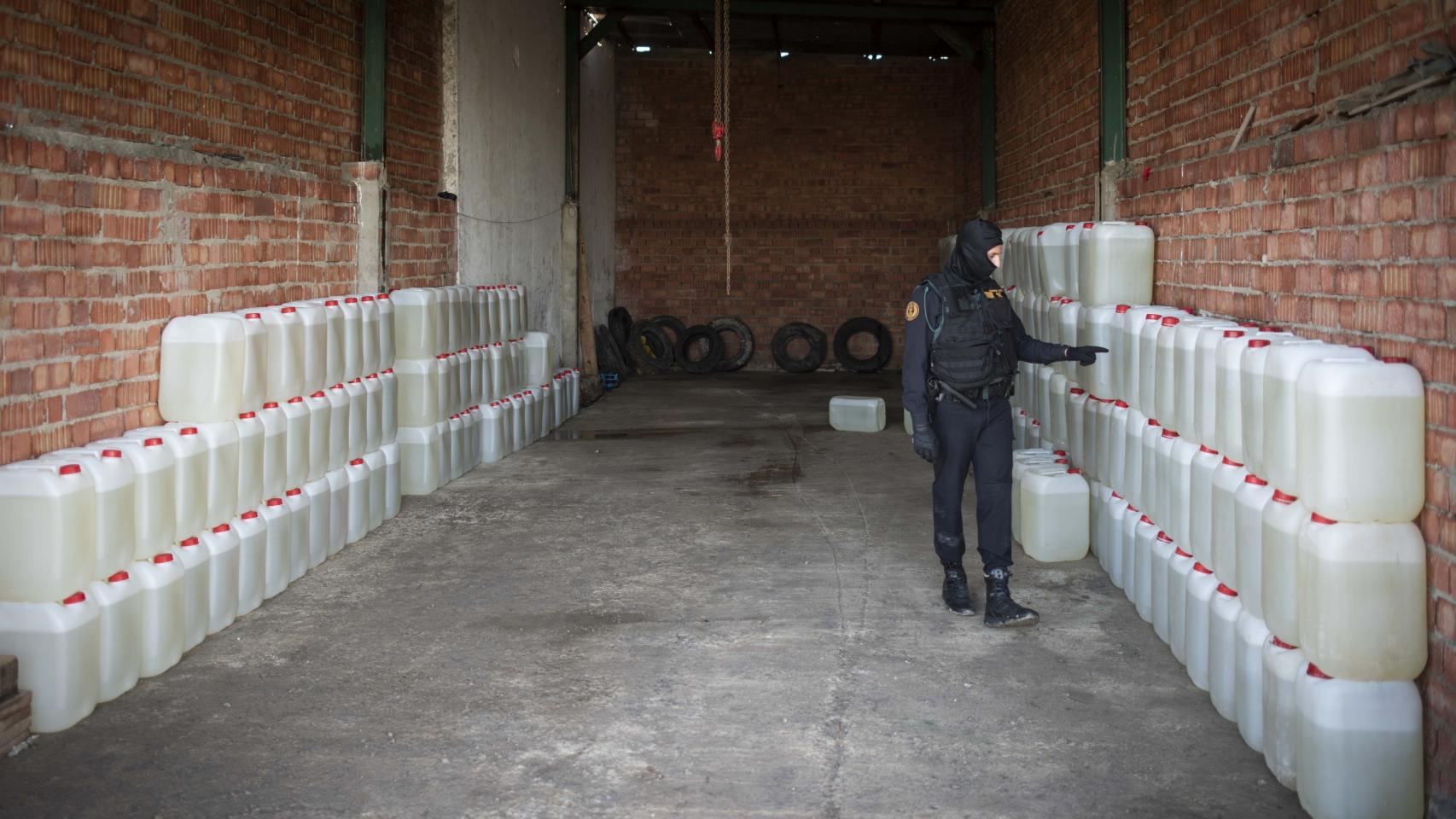 Un agente de la Guardia Civil cuenta el número de bidones de gasolina incautados en una nave de Lebrija (Sevilla).