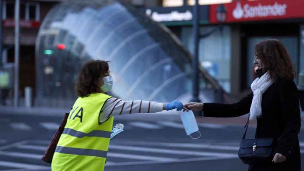 Una voluntaria de la DYA realiza una entrega de mascarilla a una mujer en la capital vizcaína.