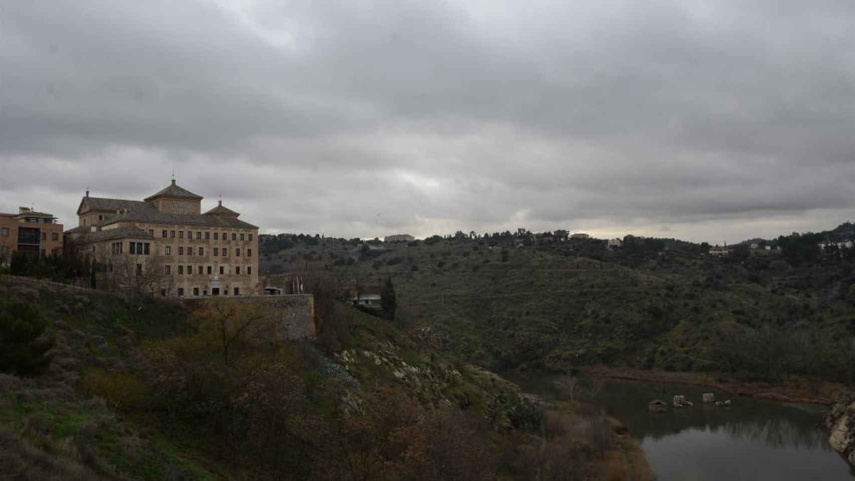 Las Cortes de Castilla-La Mancha, a la izquierda, bajo el cielo nublado de Toledo