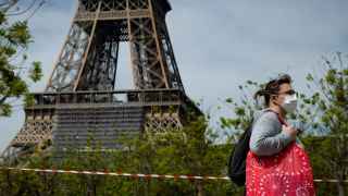 Una mujer camina con mascarilla cerca de la torre Eiffel