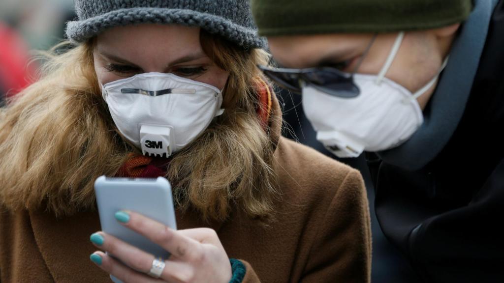 Personas con mascarillas usando el smartphone.