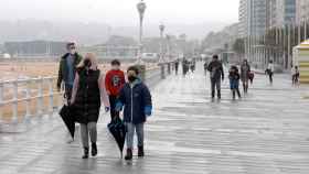 Familias pasean por el  paseo marítimo de Gijón durante el estado de alarma.