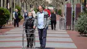 Una anciana pasea acompañada por un familiar por una avenida de Logroño.