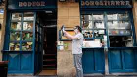 El propietario de un bar de San Sebastián limpiando la fachada de su negocio.