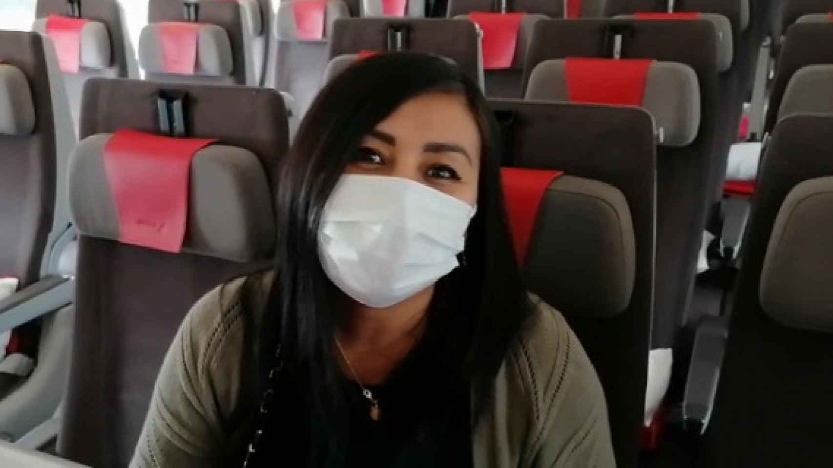 Una pasajera en un avión con mascarilla.