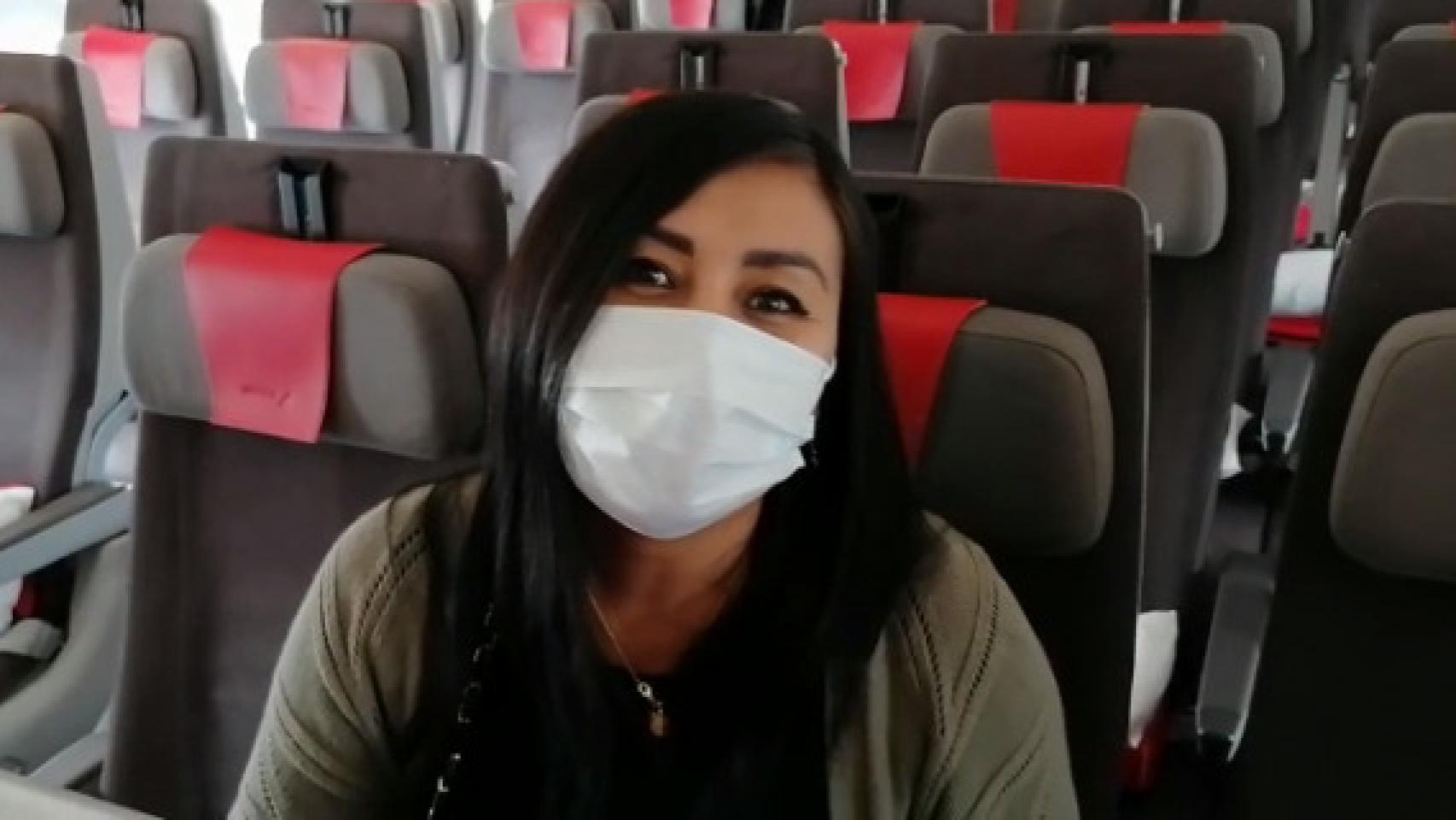Una pasajera con mascarilla a bordo de un avión.
